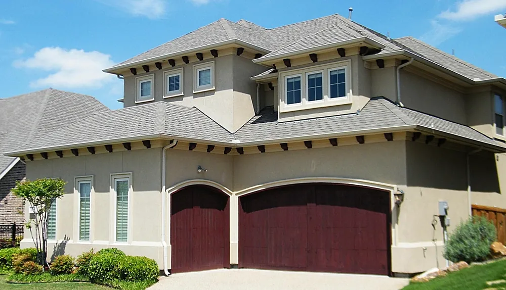 Two arched wood-look garage doors on a stucco house with a tiled roof