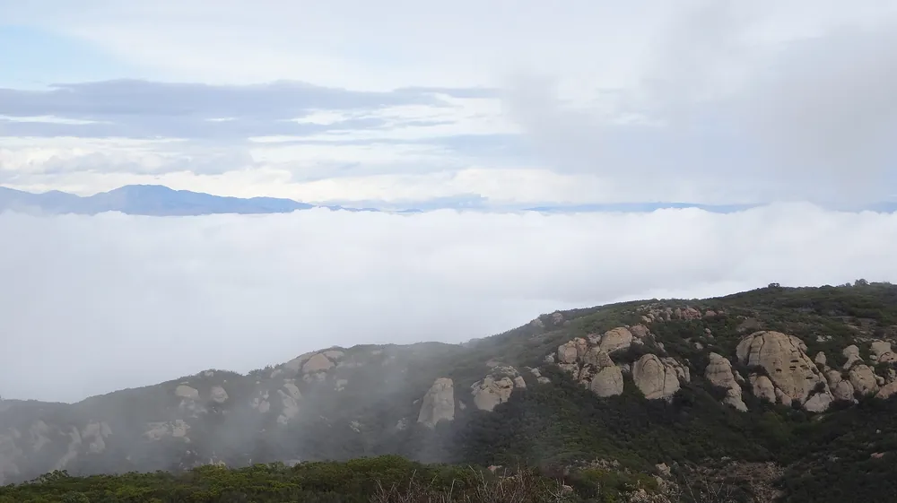 Low morning cloud filling a valley below rocky sandstone peaks