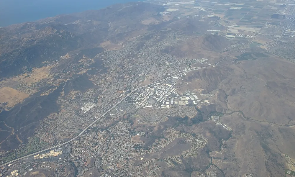 Aerial view of a valley city and freeway between dry hills