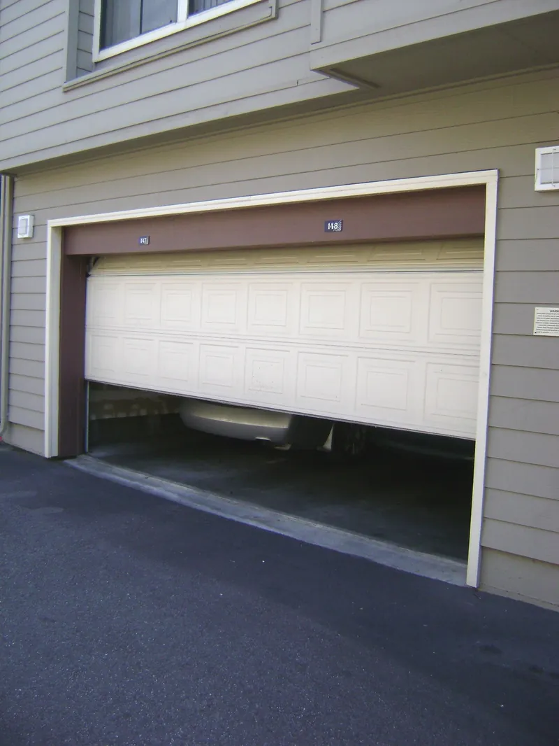 Wide sectional garage door raised halfway above a paved driveway