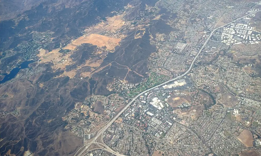 Aerial view of a valley city where two freeways meet, with brown hills on every side